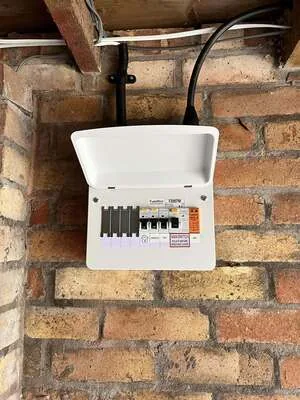 Compact consumer unit mounted on a brick wall in a garage