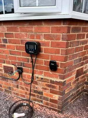 Compact smart EV charger fitted below a bay window on a brick house