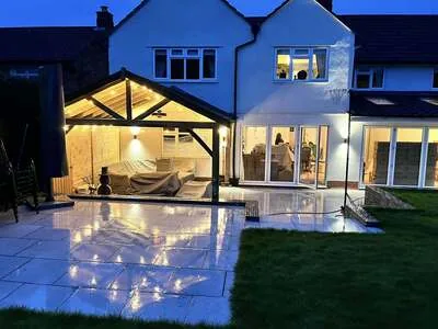 Garden room and patio lit at night by outdoor wall and ceiling lights