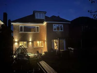 Detached house at dusk lit by up and down exterior wall lights