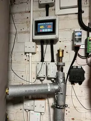 Digital controller, isolators and wiring installed beside hot water pipework in a utility room