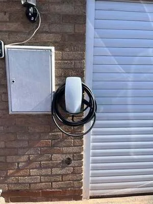 White EV charger installed beside a garage door and meter box