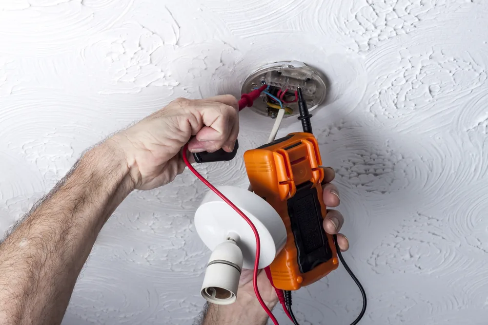Electrician testing a ceiling rose with a multimeter