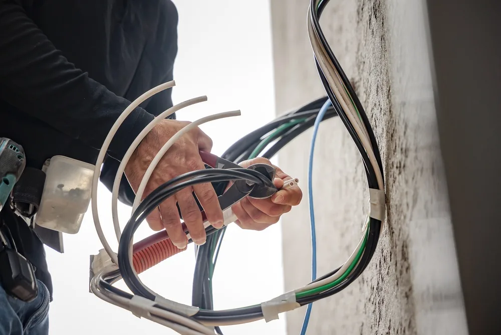 Electrician pulling new cables through a wall after spotting the signs you need a rewire